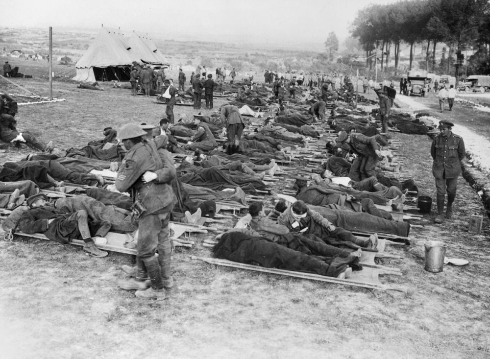 Wounded British soldiers, waiting to be taken to a casualty clearing station, lie on stretchers near Albert. 1916.